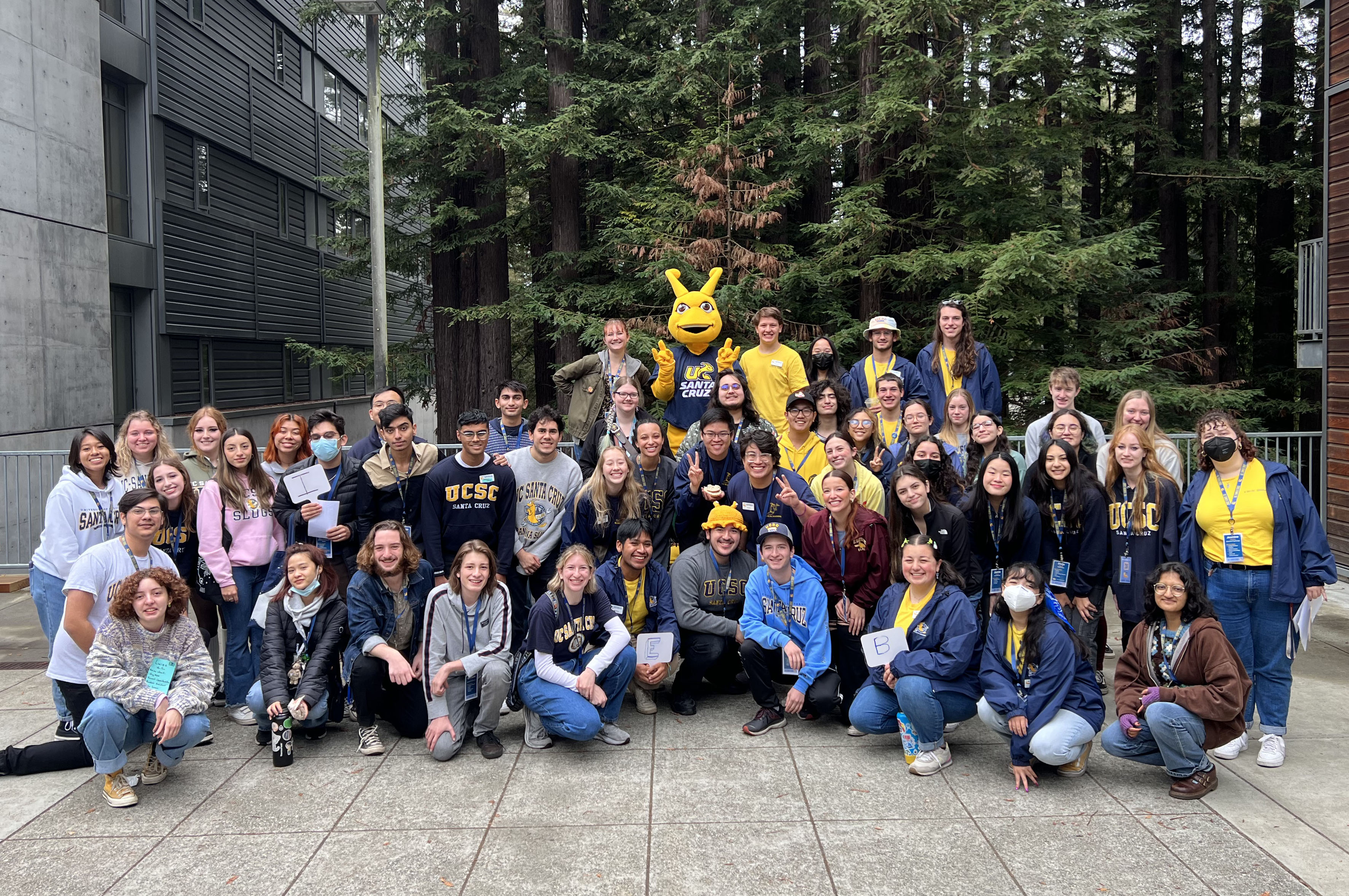 A group of student tour guides posing with Sammy the Slug